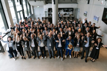 Gesamtes Gruppenfoto, alle heben ihre Hände in die Höhe